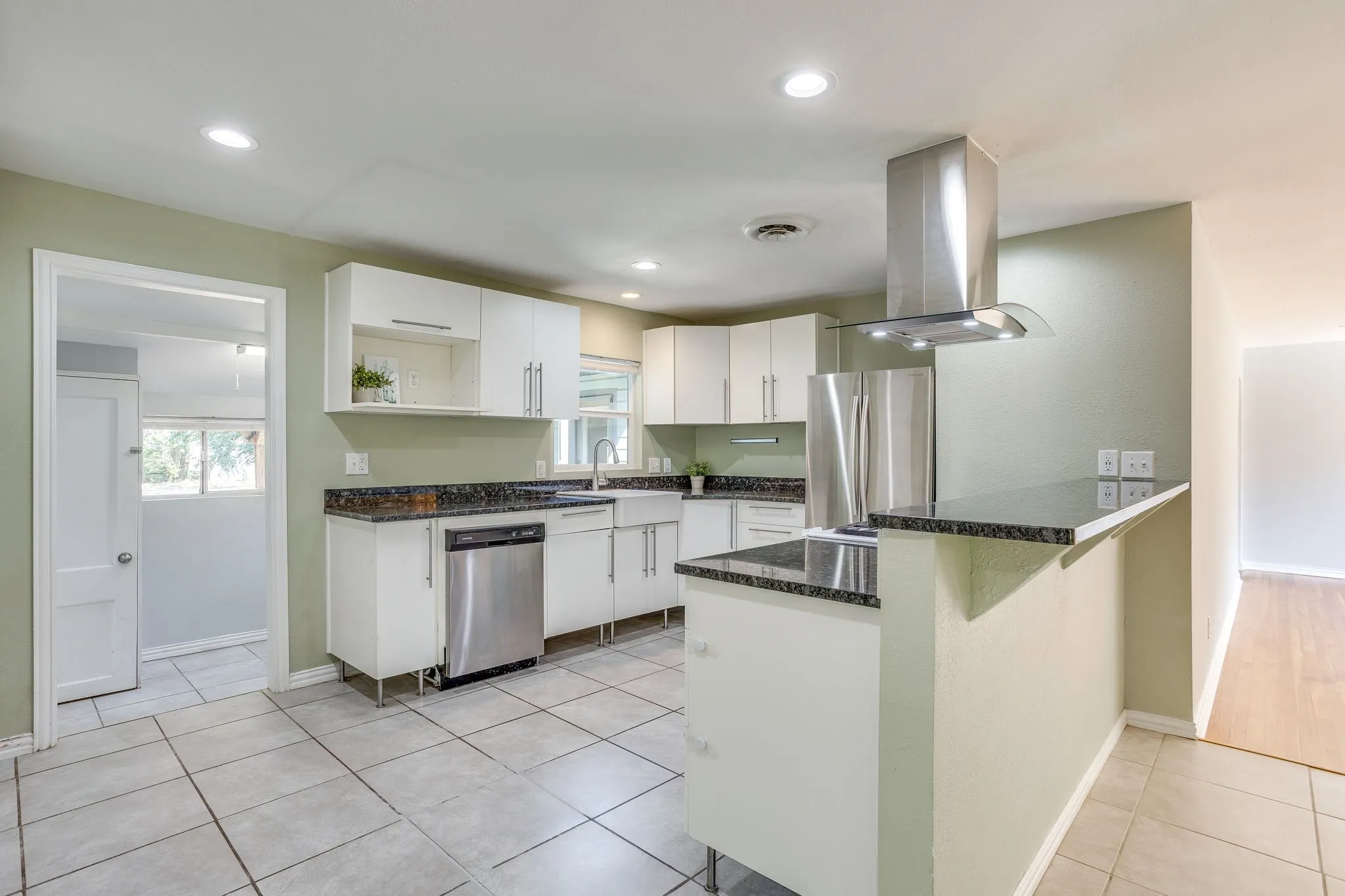 Modern kitchen featuring white cabinetry, dark stone countertops, stainless steel appliances, recessed lighting, and tile flooring