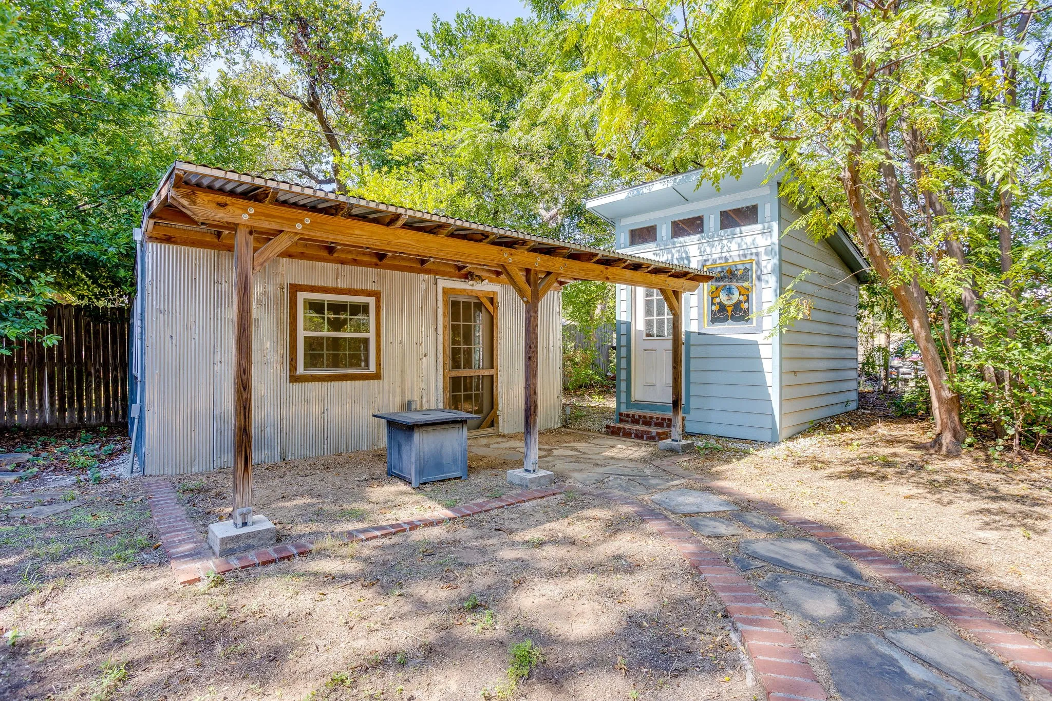 Two distinct outbuildings featuring wood siding, metal roofing, and multiple windows