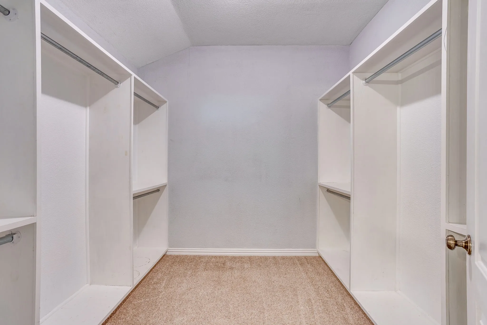 Built-in closet organization system featuring white shelving and chrome hanging rods
