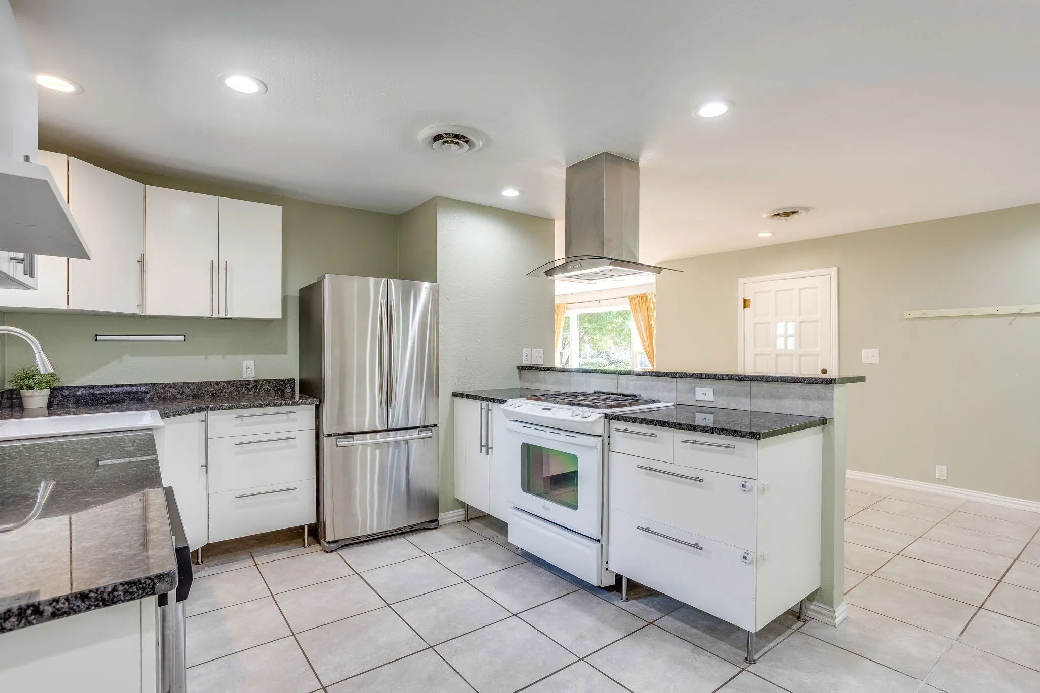 Kitchen featuring white cabinetry, dark stone countertops, stainless steel appliances, tile flooring, and a range hood