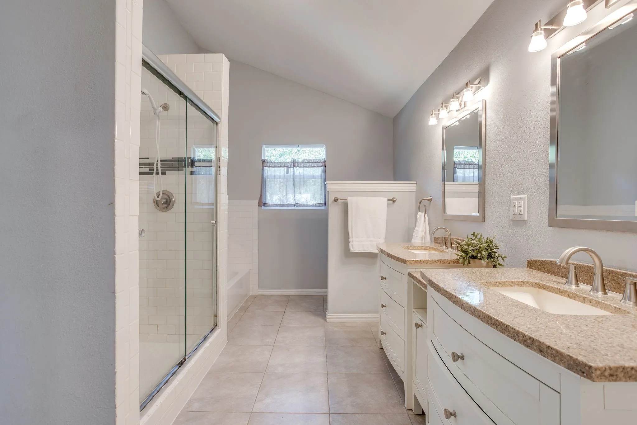 Bathroom featuring a dual vanity with undermount sinks, stone-finish countertops, and chrome fixtures
