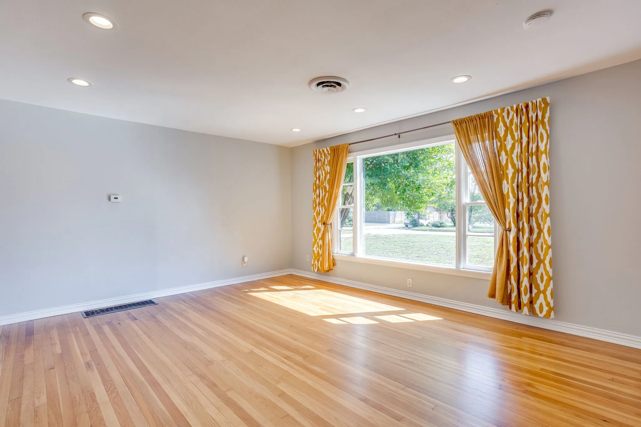 Hardwood flooring and recessed lighting illuminate this bright interior, featuring a large window