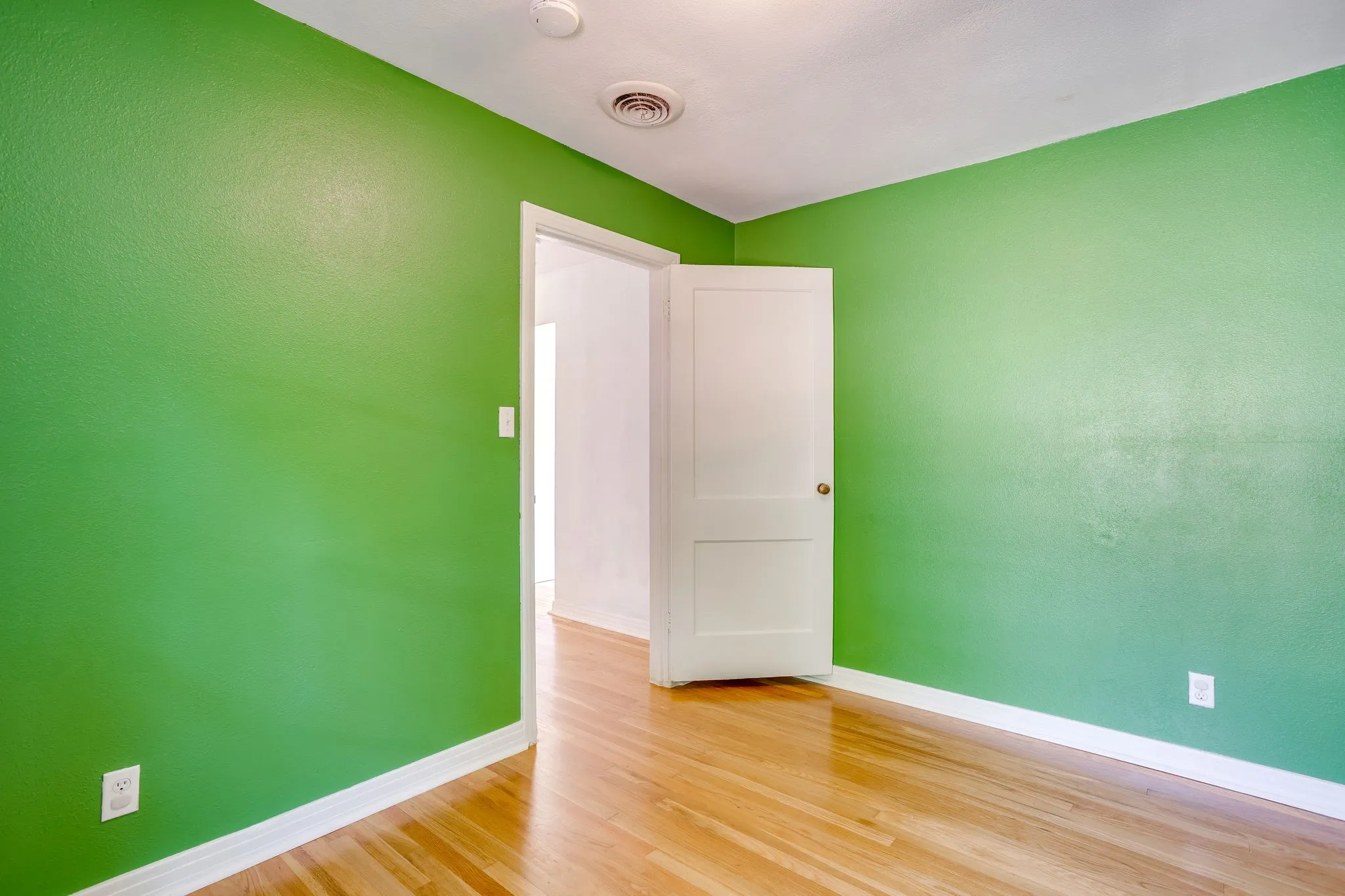 Hardwood flooring, painted walls, white trim, recessed lighting, and a paneled door