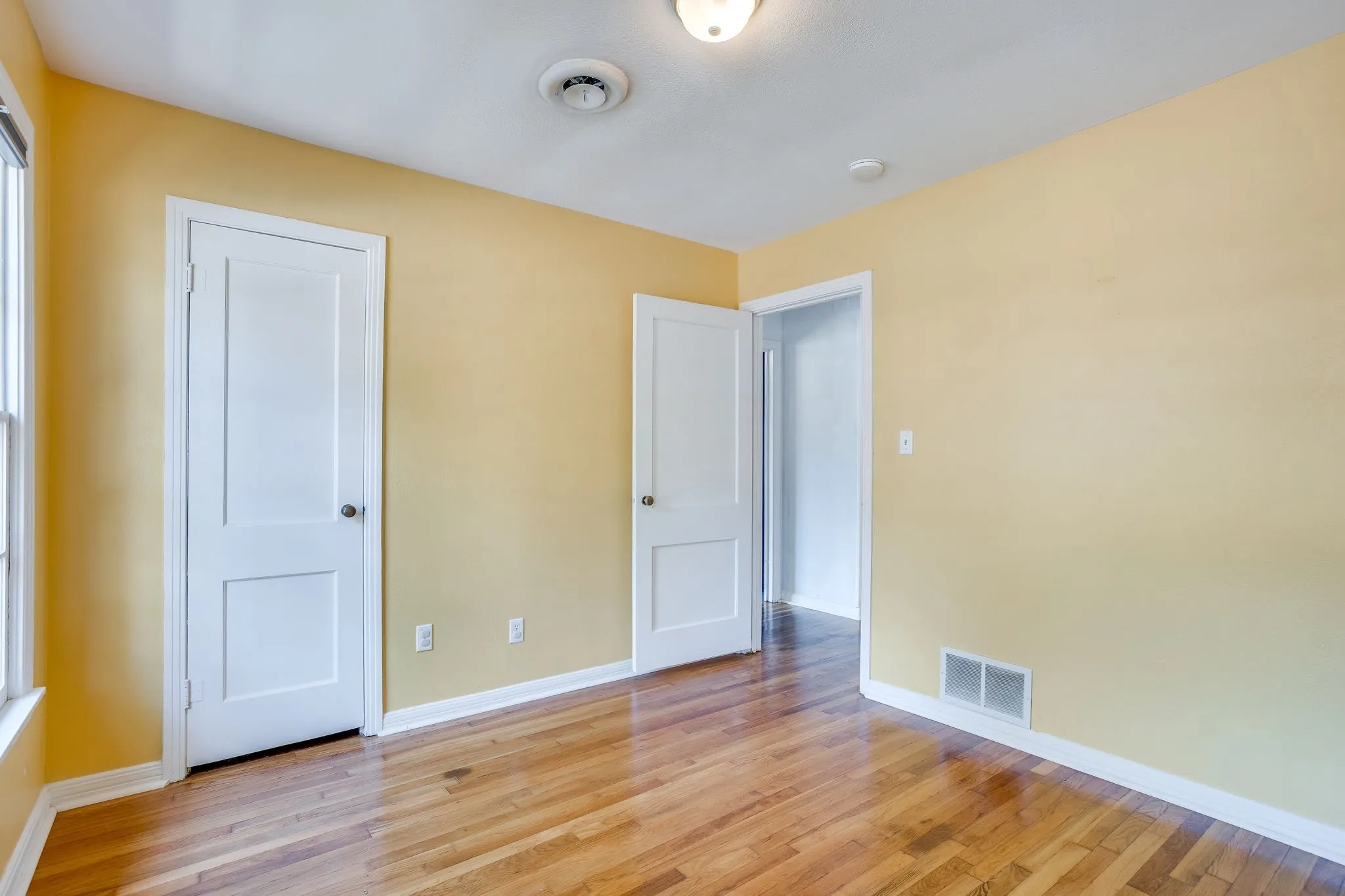 Wood-finish flooring with white trim and paneled doors