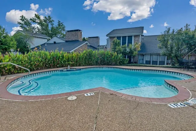 In-ground pool with stone-texture decking, tile trim, and integrated step entry