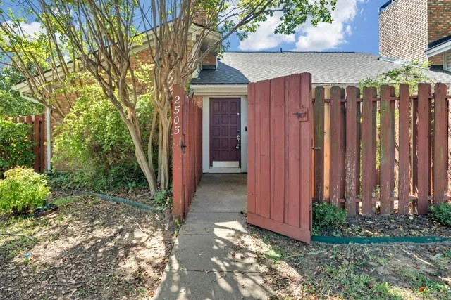 Brick exterior featuring a private gated entry, a paneled front door, and a paved walkway