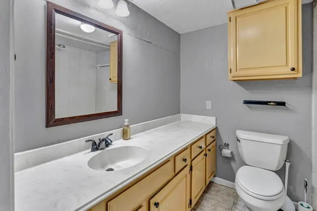 Bathroom featuring an expansive vanity with solid-surface countertop, integrated basin, wood-finish cabinetry, matching wall-mounted storage cabinet, and framed mirror