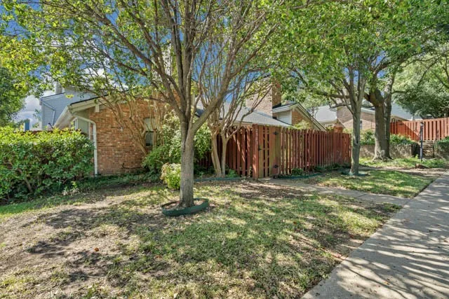 Brick exterior facade featuring a vertical wood privacy fence and mature trees