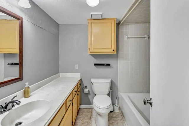 Bathroom featuring an extended countertop vanity, light-finish cabinetry, wall-mounted upper storage cabinet, and a tiled tub-shower combination