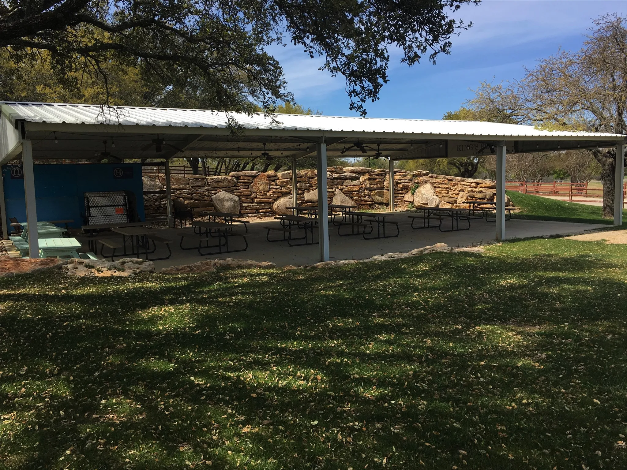 Covered outdoor structure with a metal roof, concrete flooring, and stone wall features