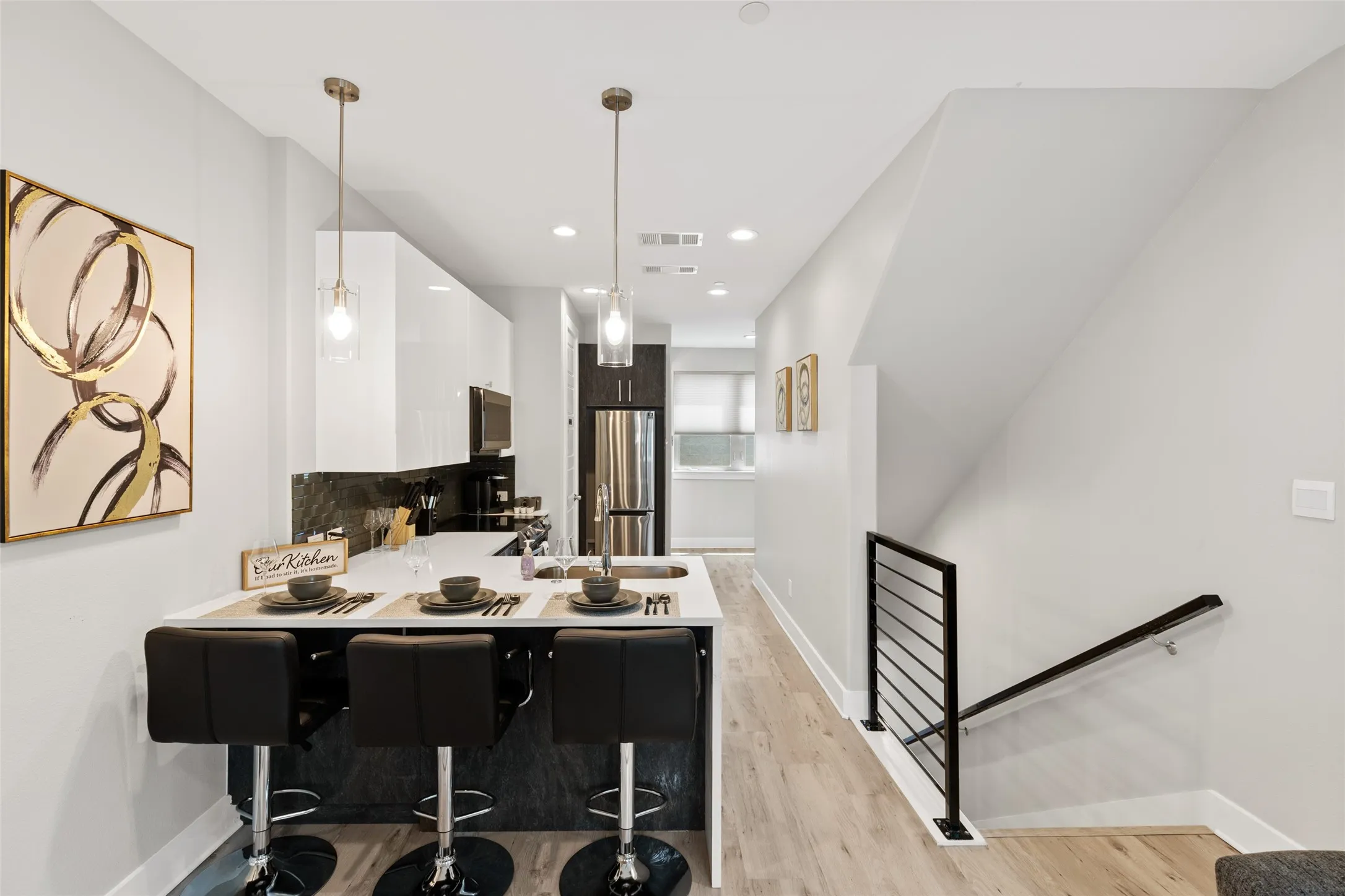 Modern kitchen featuring white upper cabinetry and a dark lower island with a light-colored countertop