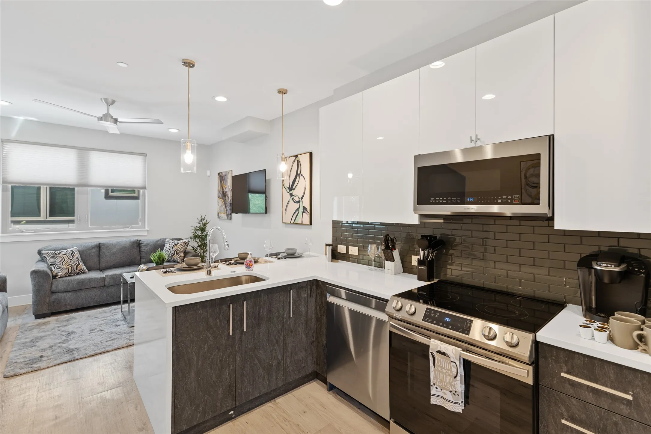 Modern kitchen with stainless steel appliances, white countertops, and dark subway tile backsplash