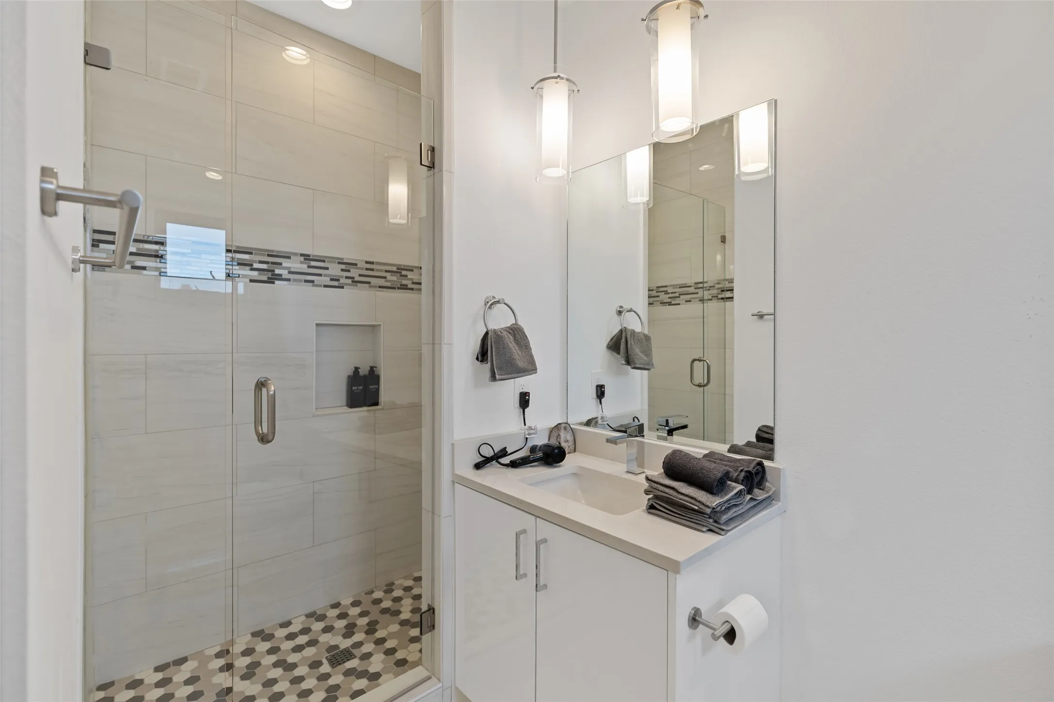 Glass-enclosed shower with subway tile surround and mosaic accent