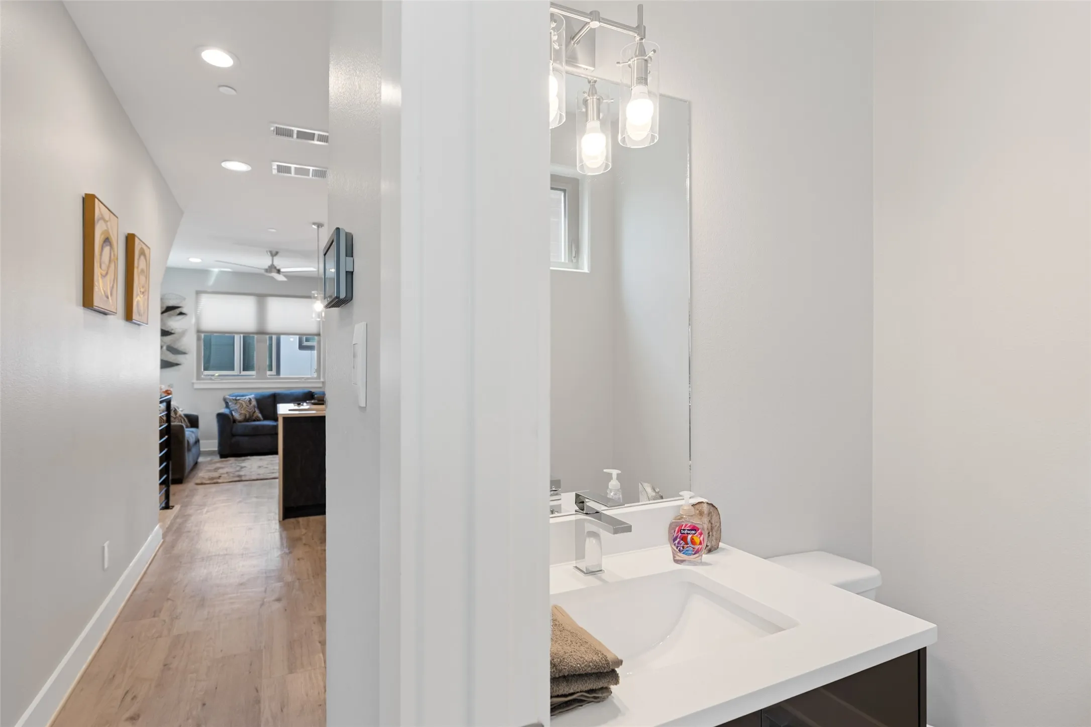 Bathroom vanity with integrated sink, chrome faucet, and overhead lighting