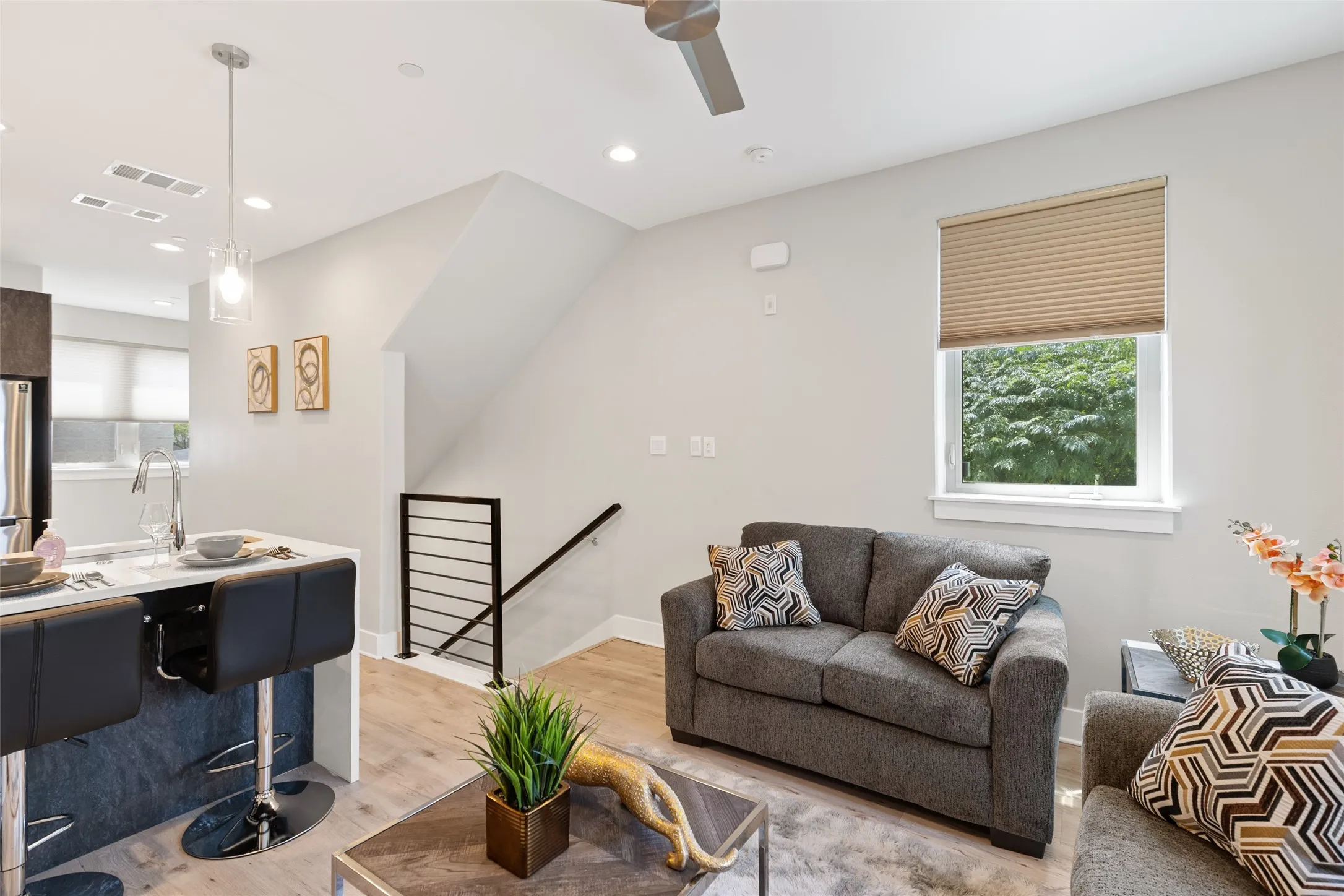 Open-concept living space with wood-finish flooring, a contemporary ceiling fan, and recessed lighting