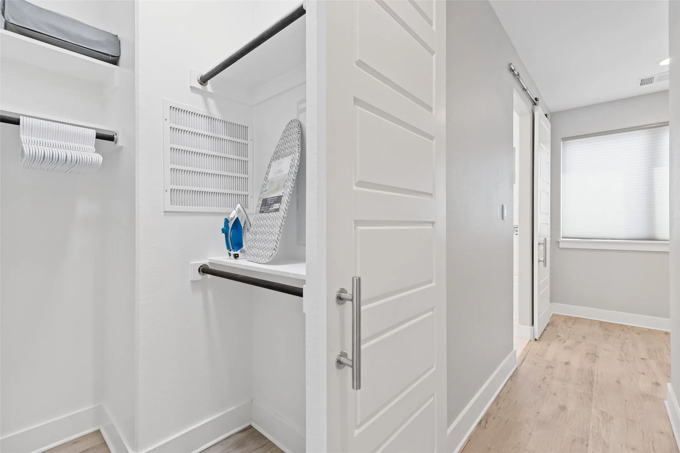 Hallway with wood-finish flooring, a window with blinds, and white walls