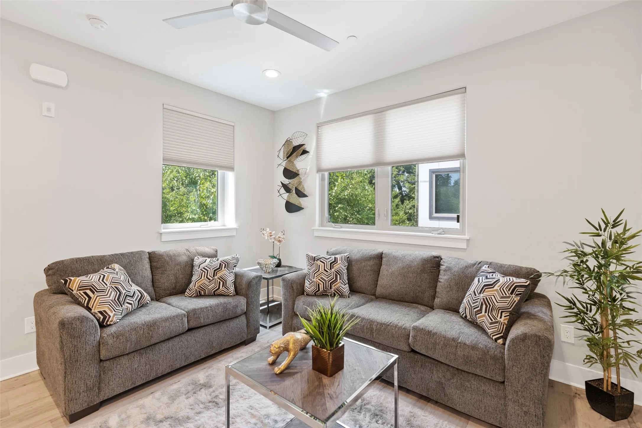 Recessed ceiling lighting, modern ceiling fan, wood-finish flooring, multiple windows, and a neutral wall color