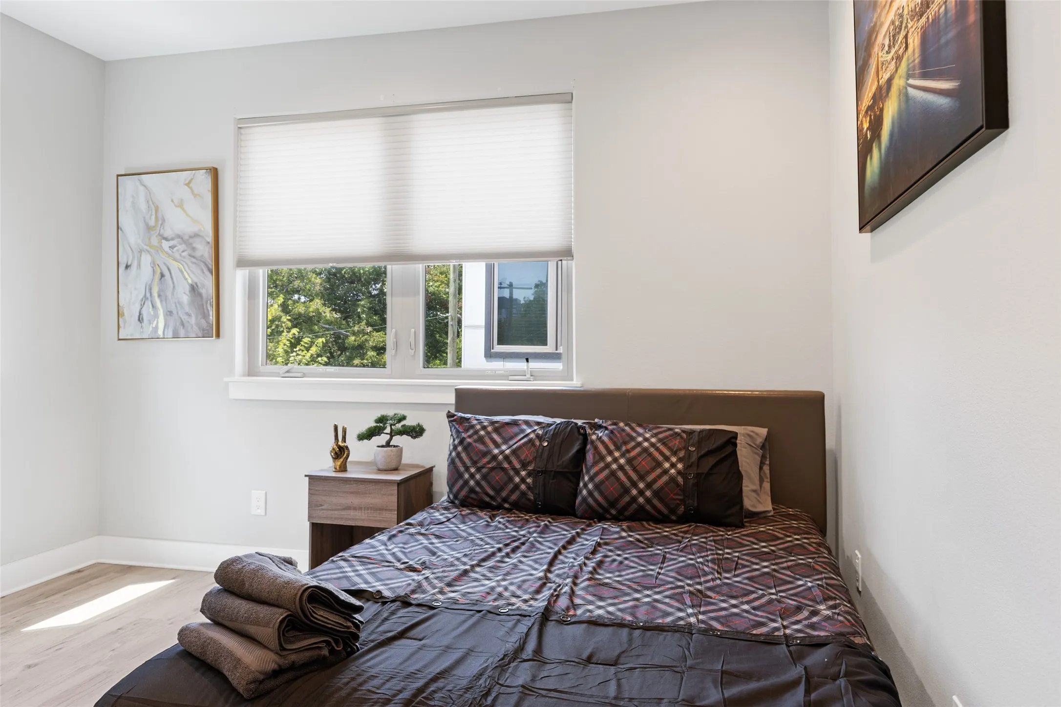 Light wood-finish flooring, white walls, and a window with a pleated shade