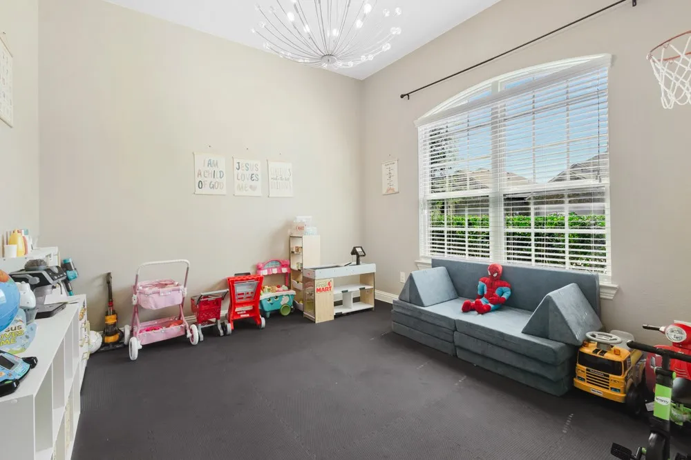 This sec. bedroom shows with removable workout flooring.  It has been removed to showcase the laminate flooring in place.  Arched window with blinds, high vaulted ceilings, a modern light fixture, are a few of the features that make this room the one the kids will call dibs on.