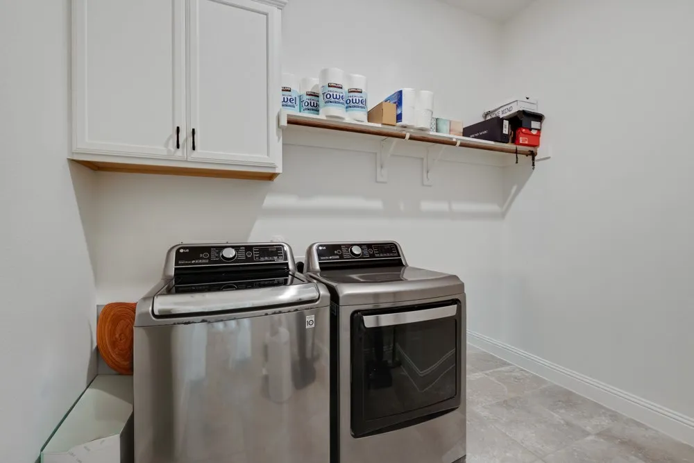 The oversized utility room offers White shaker cabinetry, a hanging bar and addtl space for a fridge.