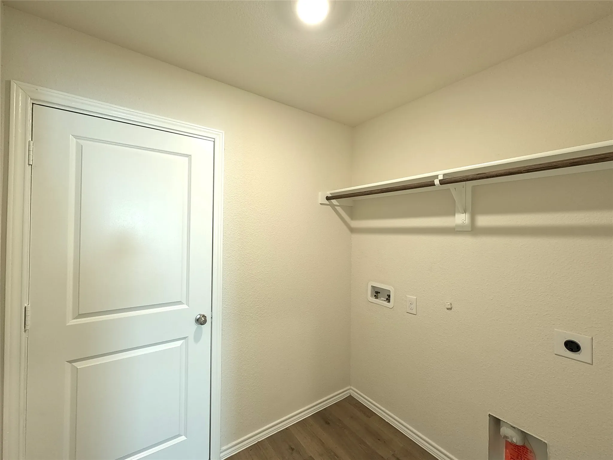 Utility area with wood-finish flooring, overhead shelving, and integrated lighting