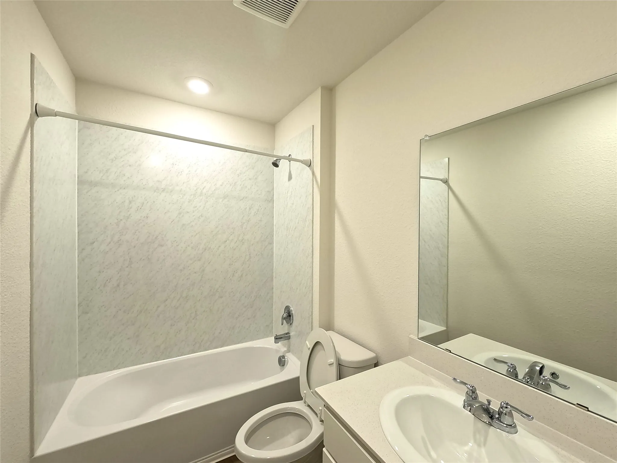 Built-in bathtub with shower, white vanity sink with chrome fixtures, and an integrated wall mirror