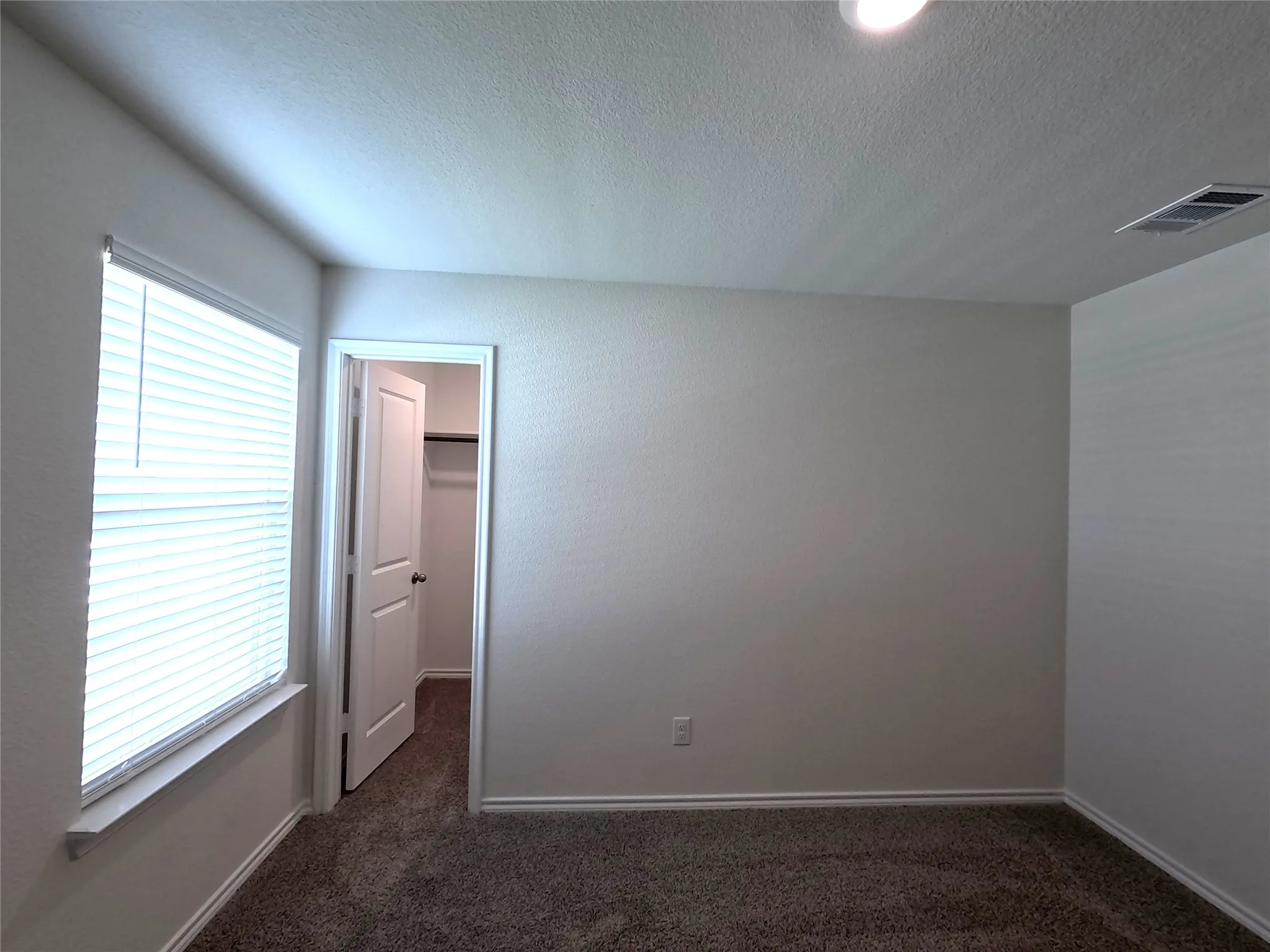 Neutral-toned walls, plush carpet flooring, and a recessed light fixture