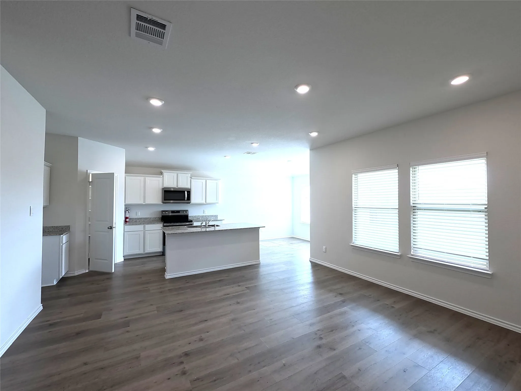 Open-concept living area with wood-finish flooring, recessed lighting, and multiple windows
