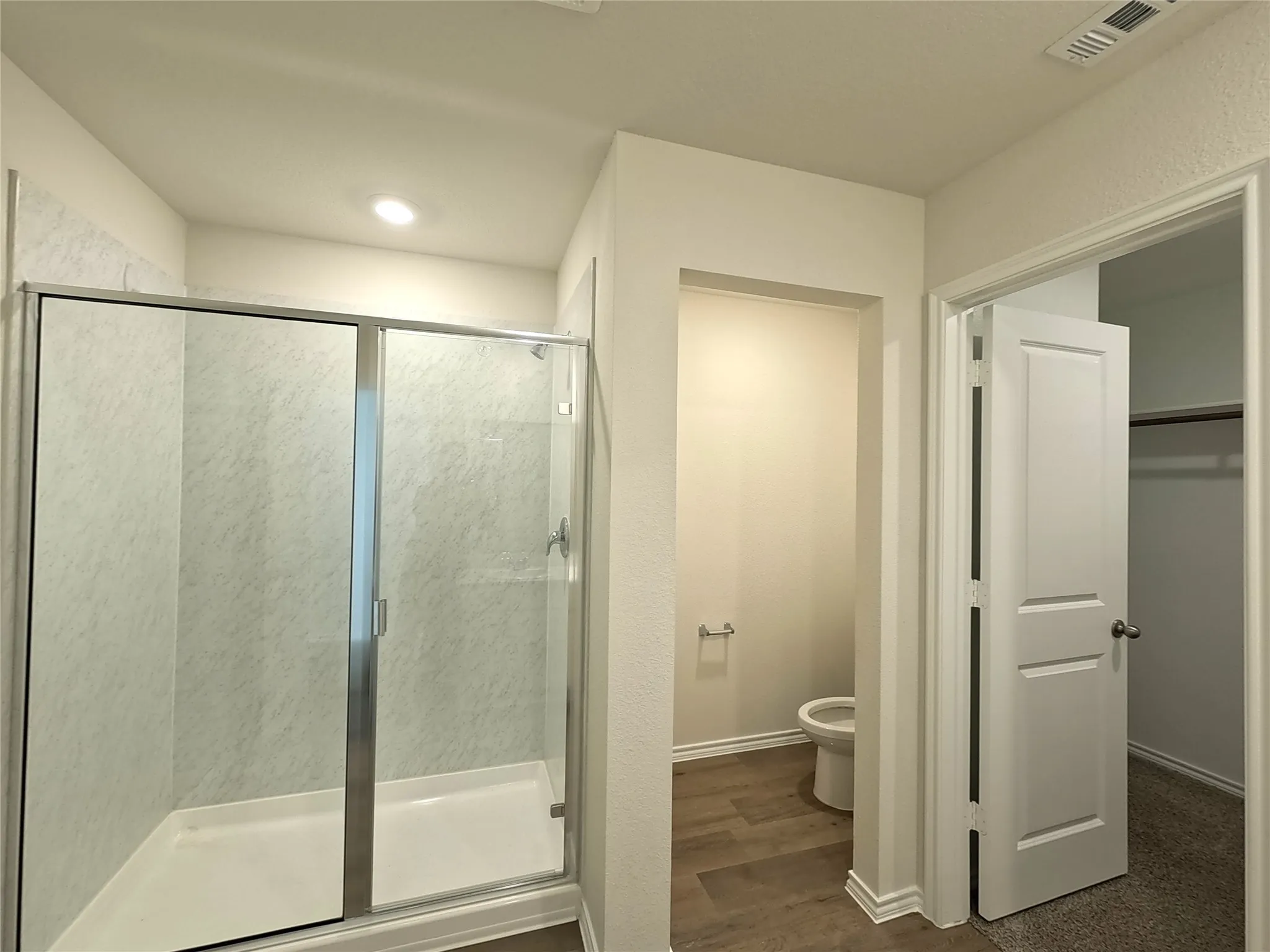 Glass-enclosed shower with a white base and patterned wall panels