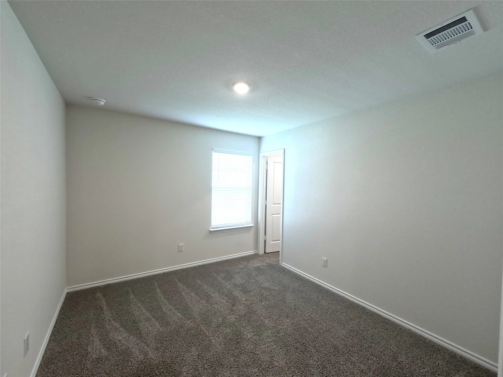 Carpeted room featuring a single window, recessed lighting, and a paneled door