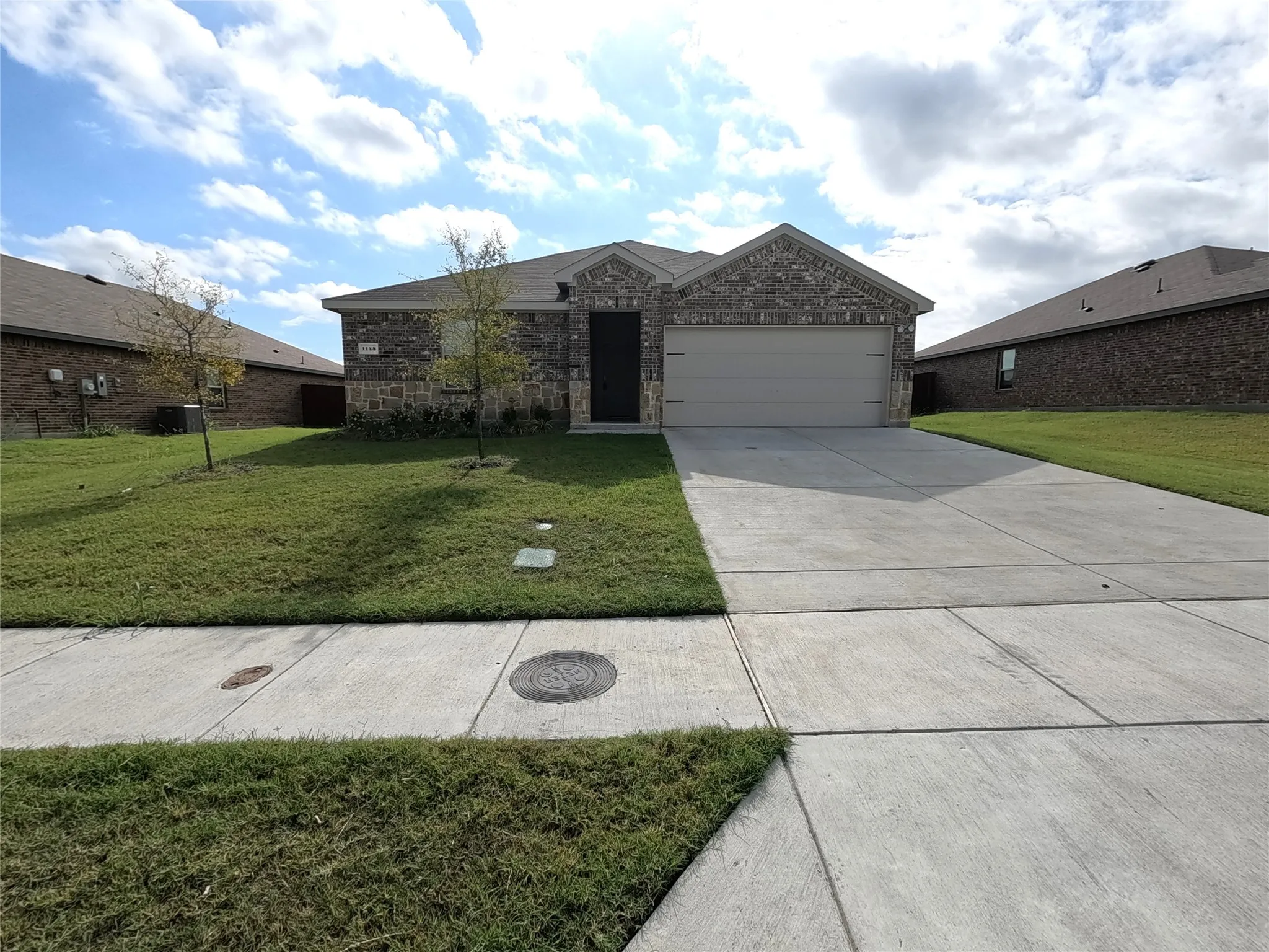 Brick facade with stone accents, attached two-car garage, and concrete driveway