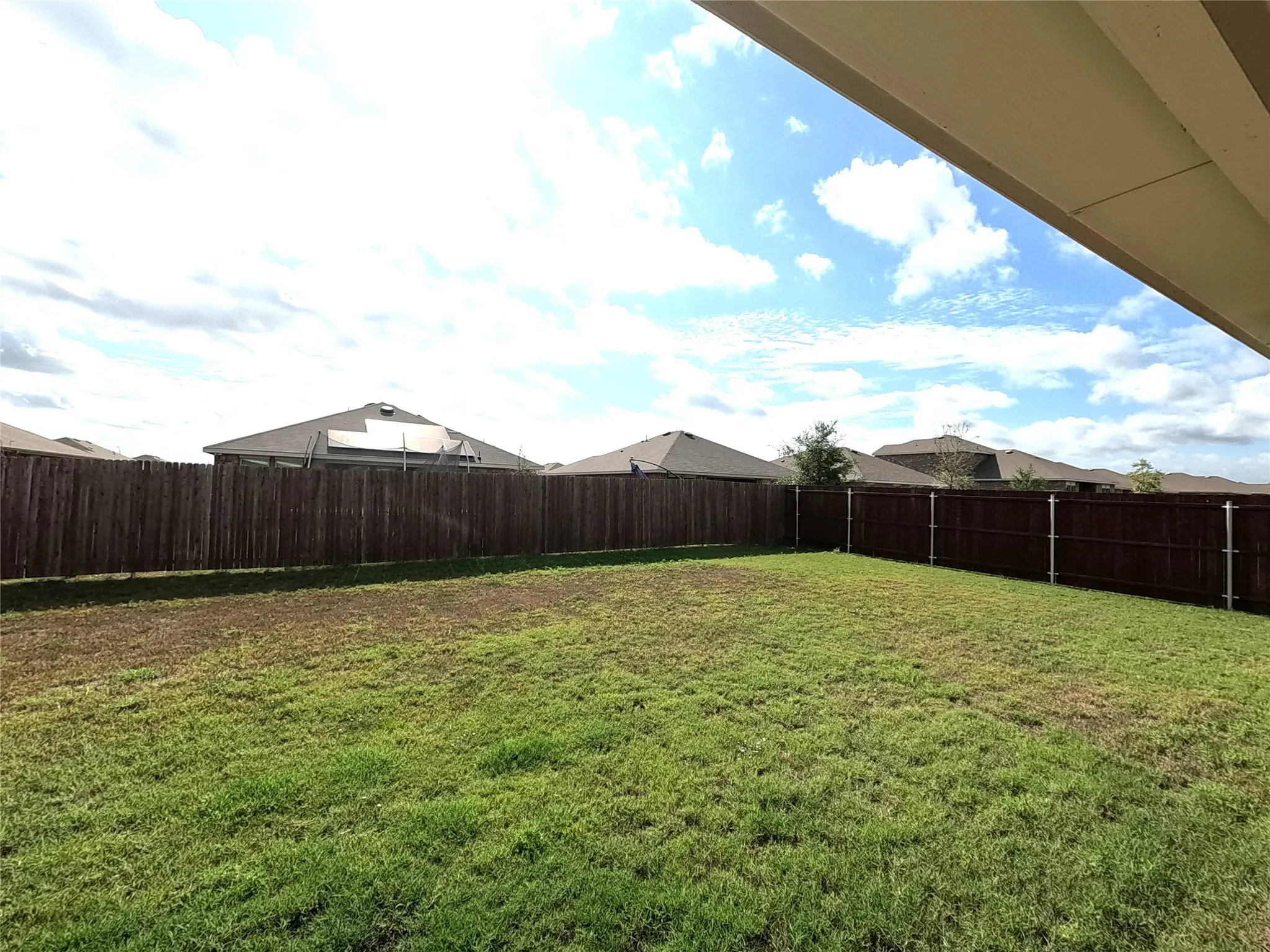 Expansive grassy yard enclosed by a tall wood privacy fence