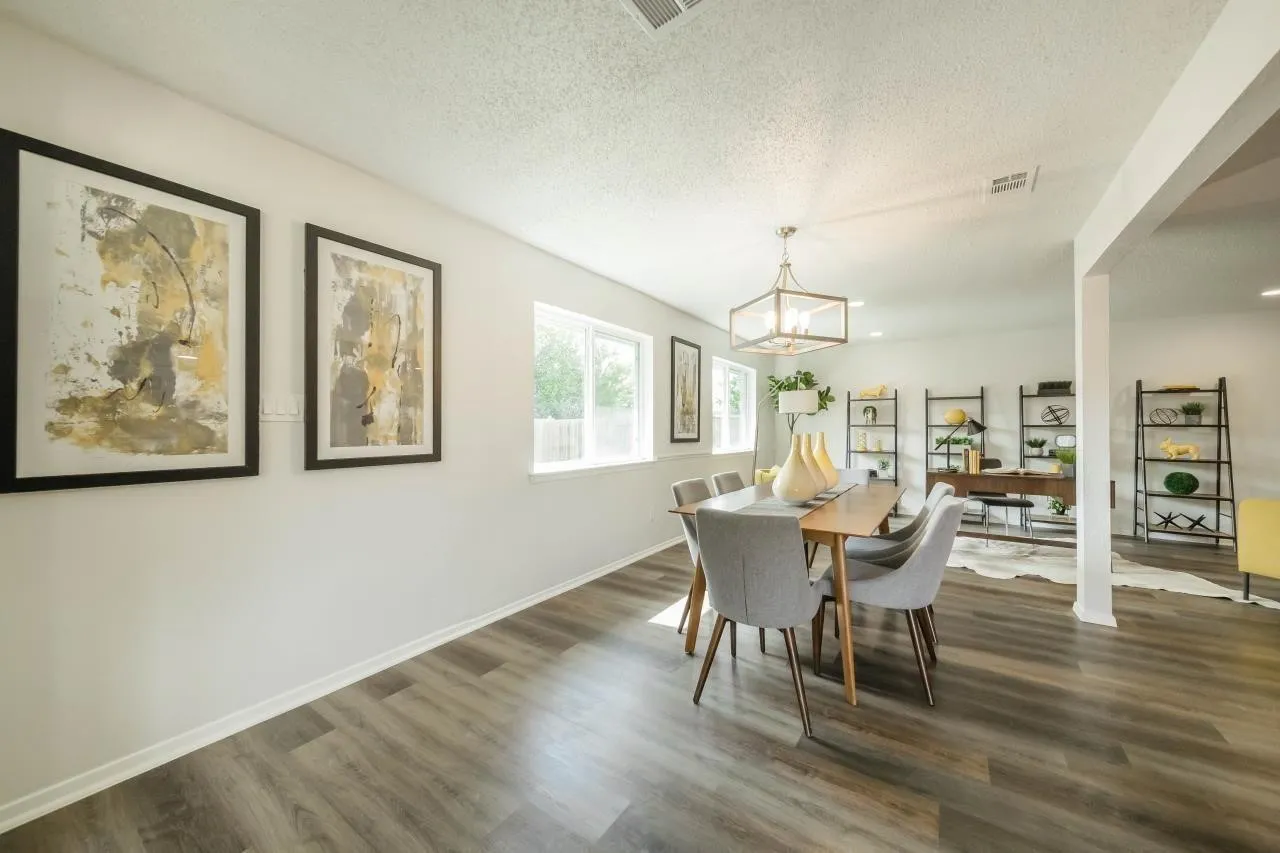 Wood-finish flooring, neutral wall color, oversized windows, and a rectangular multi-light pendant fixture