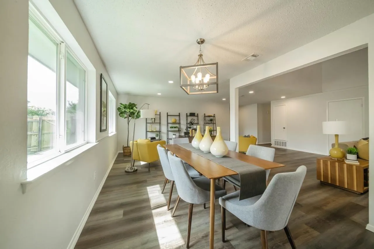 Open-concept interior featuring wood-finish flooring, a contemporary geometric pendant light fixture, and large windows with horizontal sills