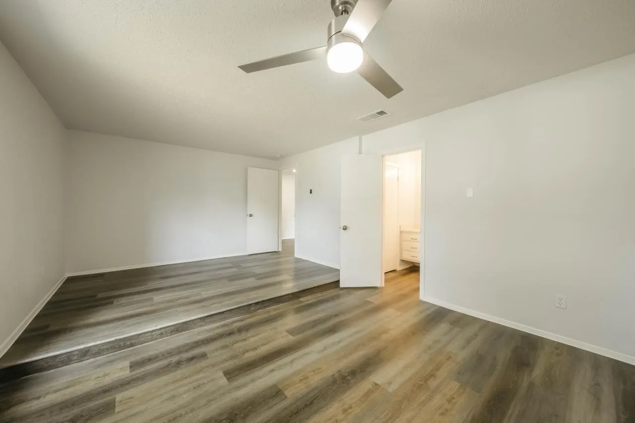 Multi-level interior space featuring wood-finish flooring, a contemporary brushed nickel ceiling fan with integrated light fixture, and neutral wall tones