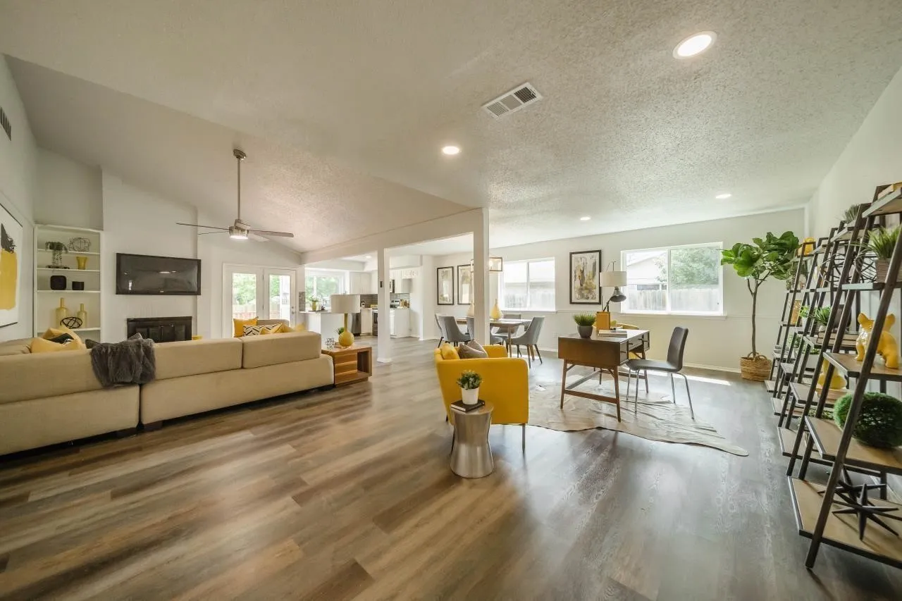Open-concept interior featuring vaulted ceilings, wood-finish flooring, recessed lighting, a fireplace with built-in shelving, and multiple windows