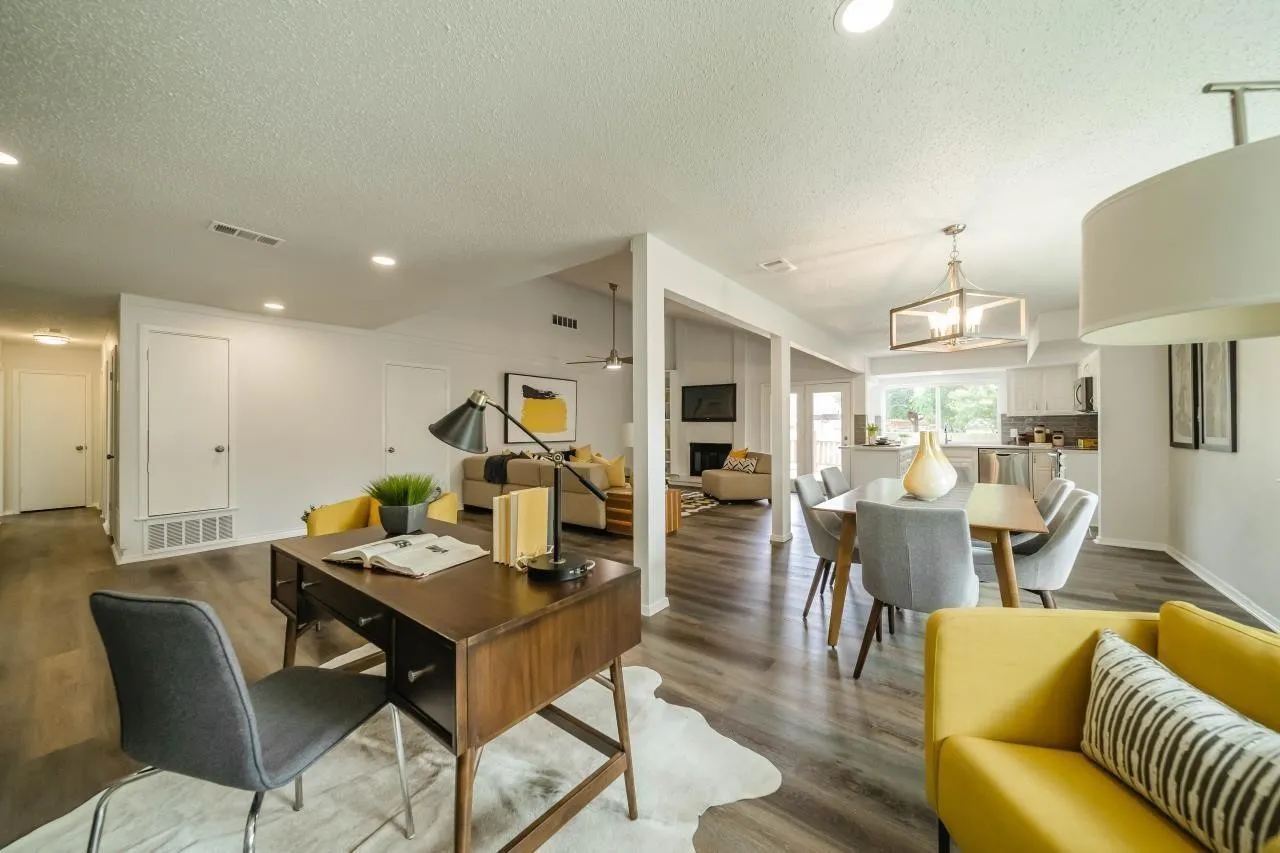 Open-concept floor plan featuring wood-finish flooring, recessed lighting, a modern geometric chandelier, and a wood-burning fireplace with a tile surround