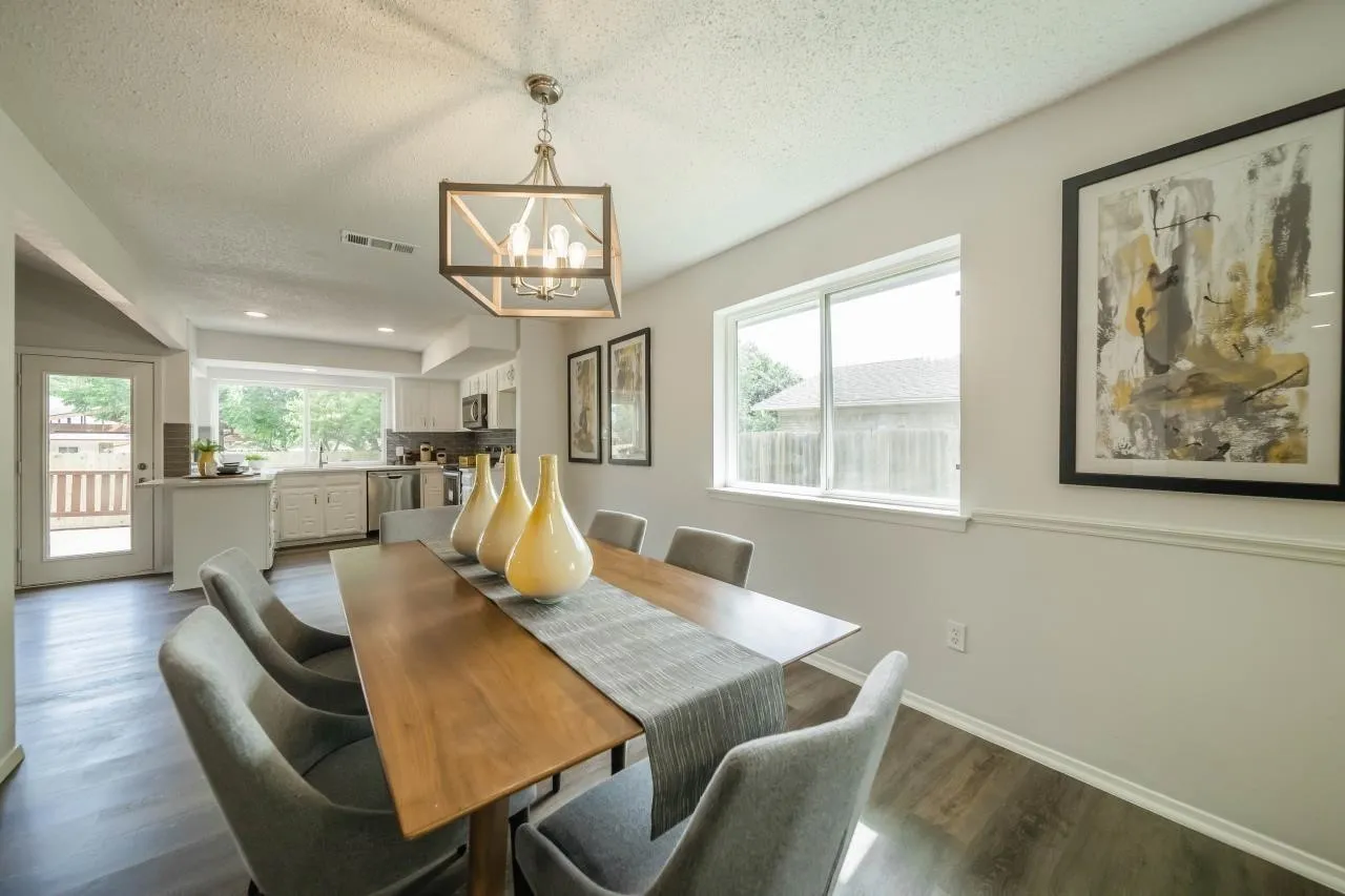 Dining area featuring wood-finish flooring, a contemporary geometric metal chandelier, chair rail molding, and a sliding glass door