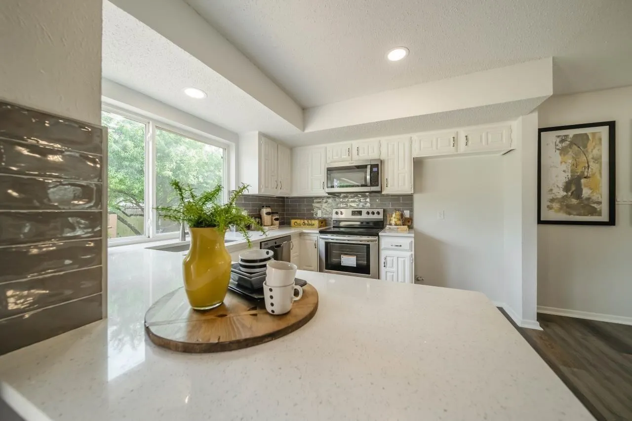 Kitchen featuring white cabinetry, quartz countertops, gray tile backsplash, stainless steel appliances, and recessed lighting