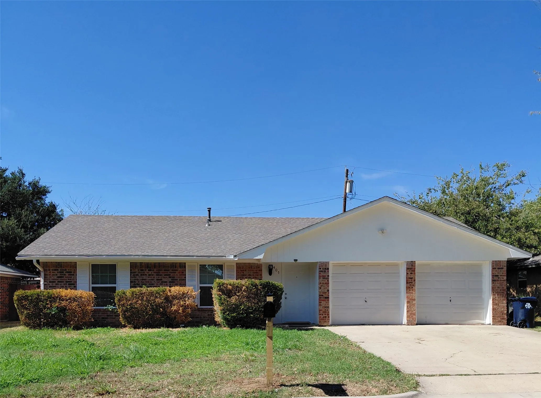 Brick and siding exterior with a gabled roofline, featuring a two-car garage and a concrete driveway