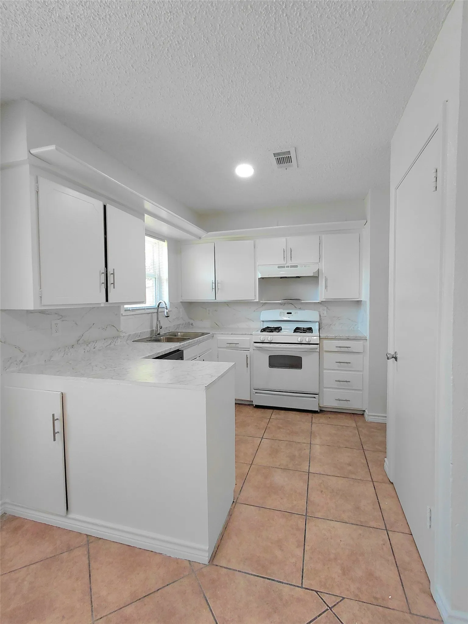 Kitchen featuring white cabinetry, white countertops, a tile backsplash, and a white range
