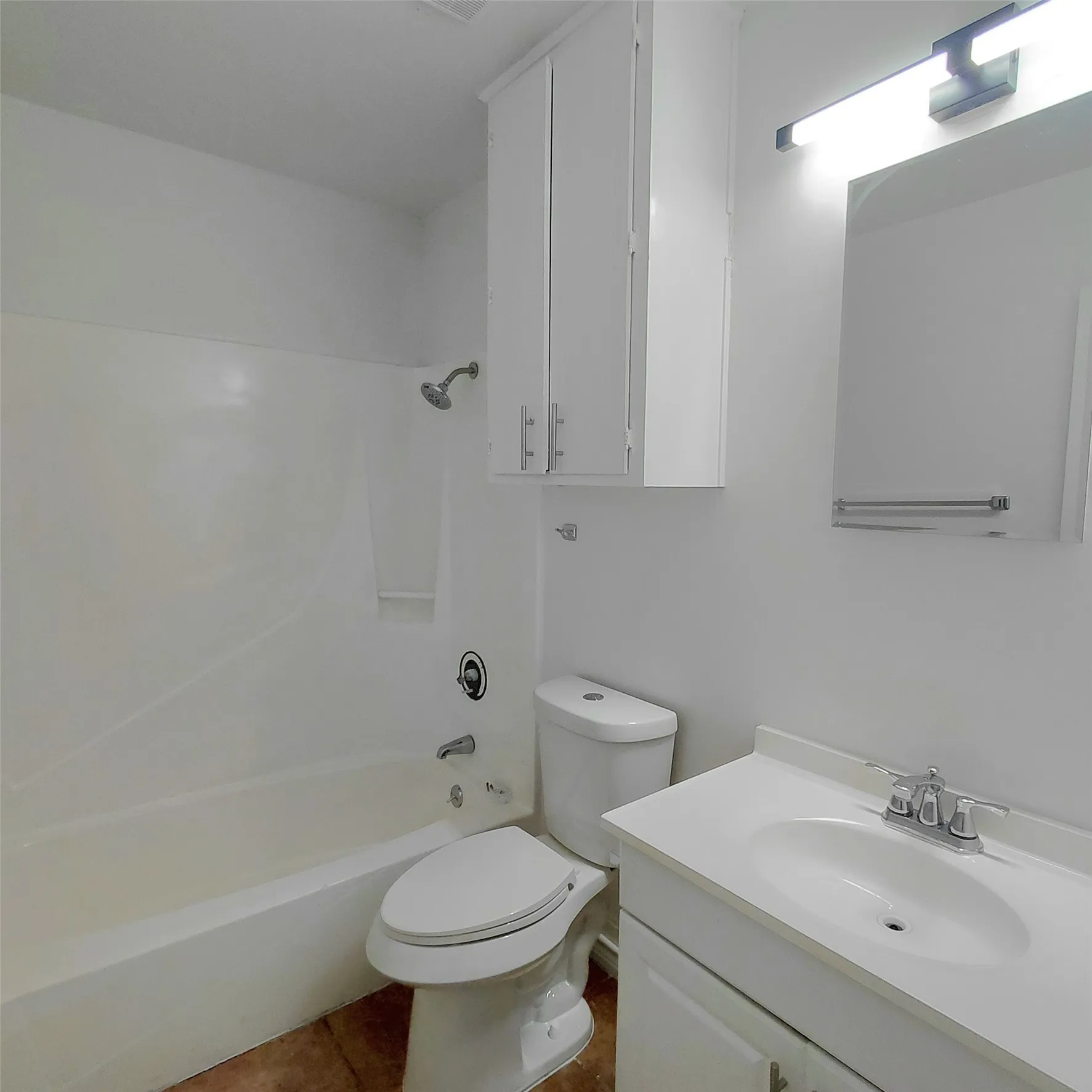 Bathroom featuring a white vanity cabinet, solid-surface countertop with an integrated sink, built-in upper storage cabinetry, and a shower-tub combination with a white surround