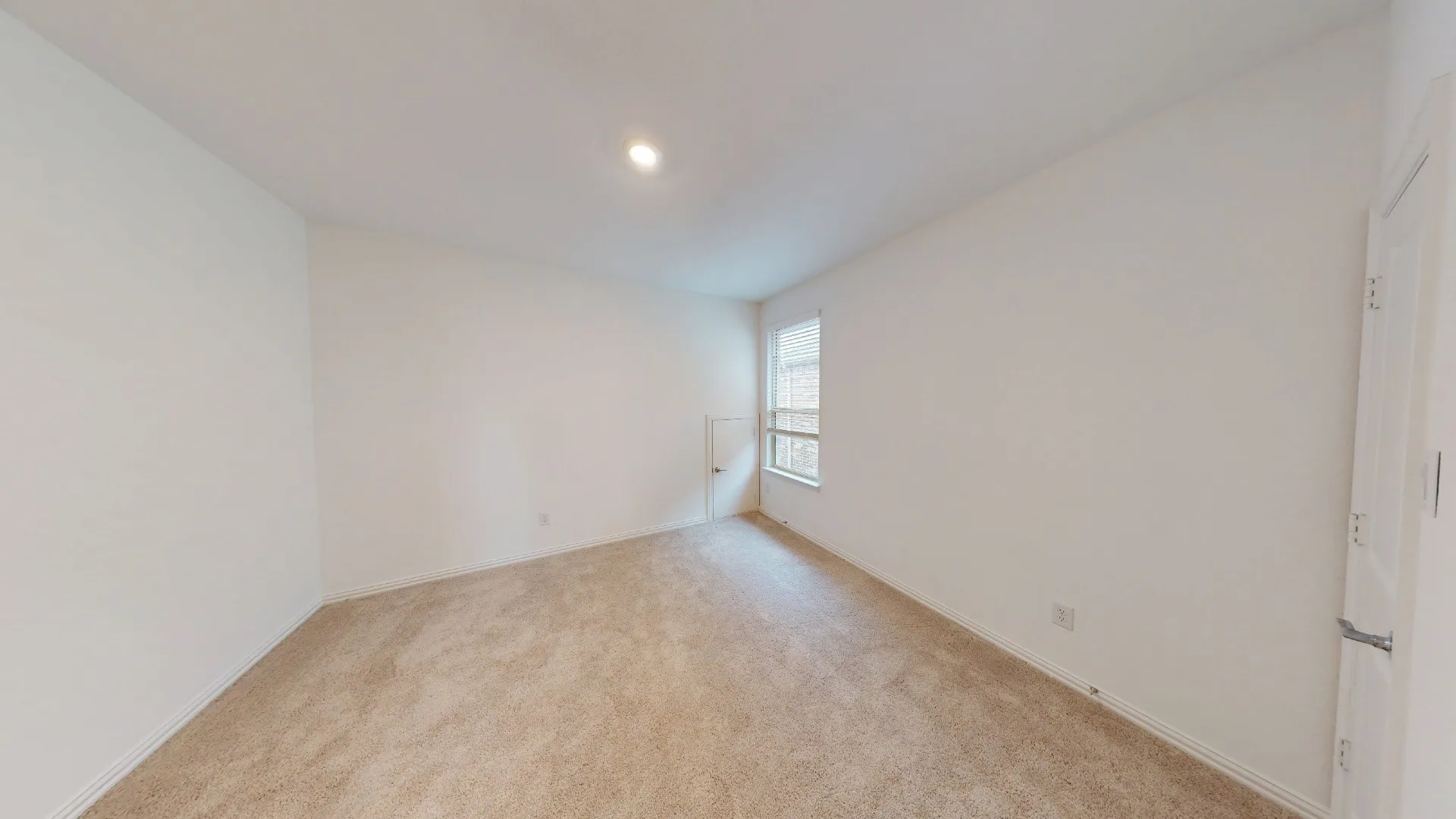 Neutral toned carpeting, recessed ceiling lighting, and a white paneled door