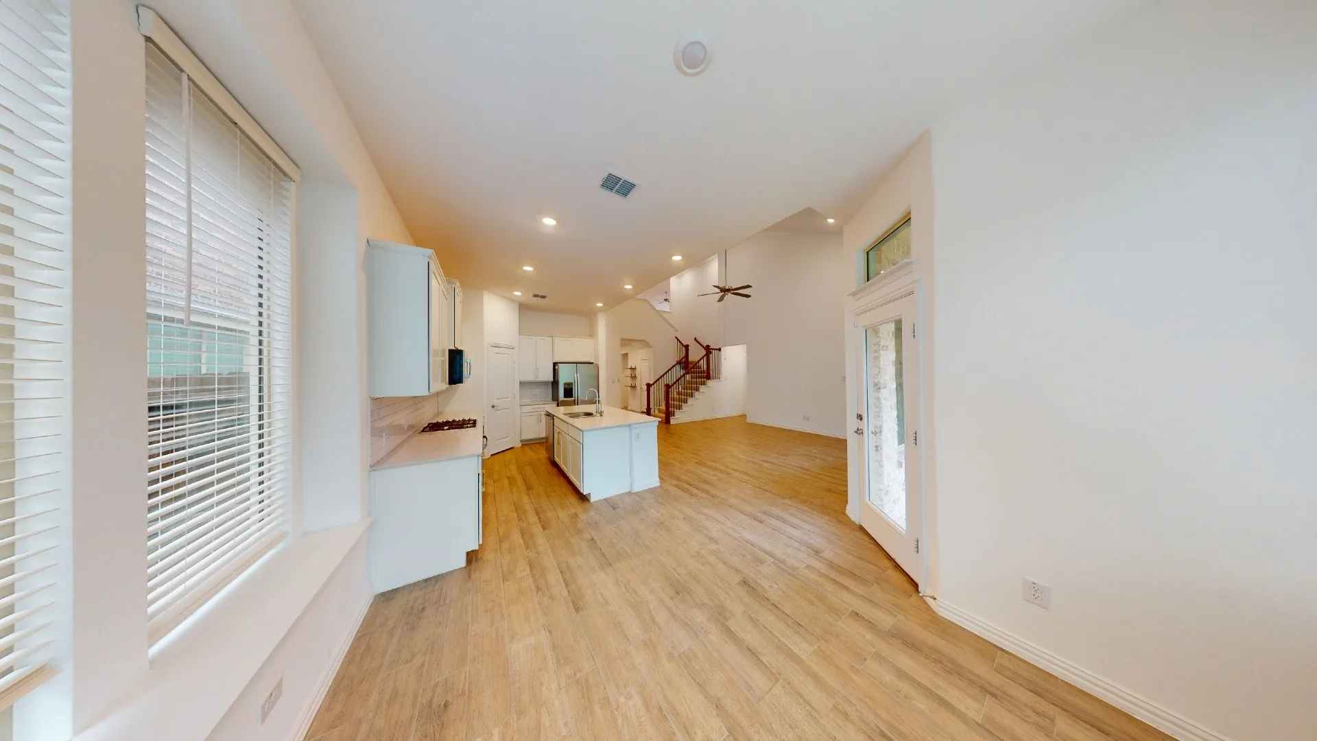 Open-concept main living area with wood-finish flooring, recessed lighting, a kitchen island, and a full-light exterior door