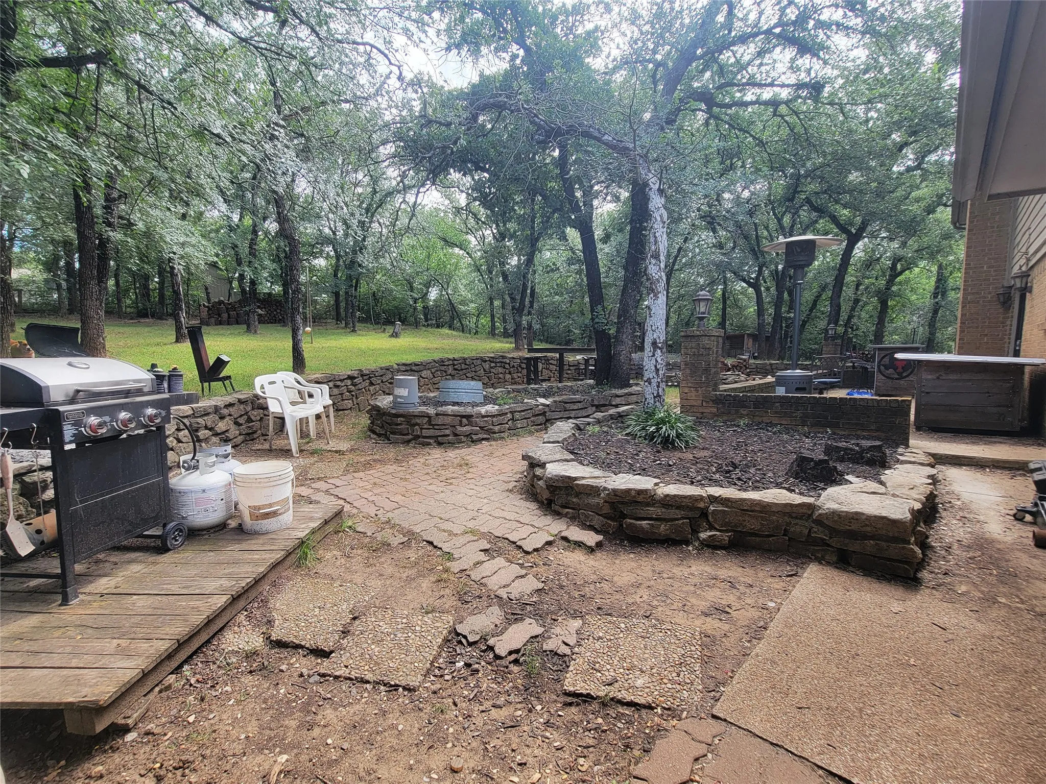Expansive outdoor patio with stone retaining walls, integrated planting beds, and a paved brick section