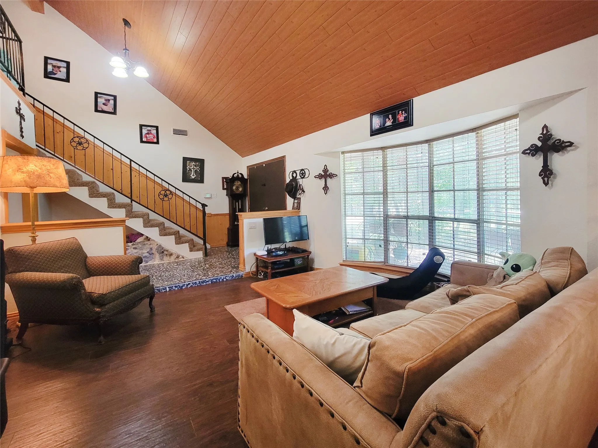 Vaulted ceiling with wood-finish paneling, an interior staircase with metal railing, and wood-finish flooring