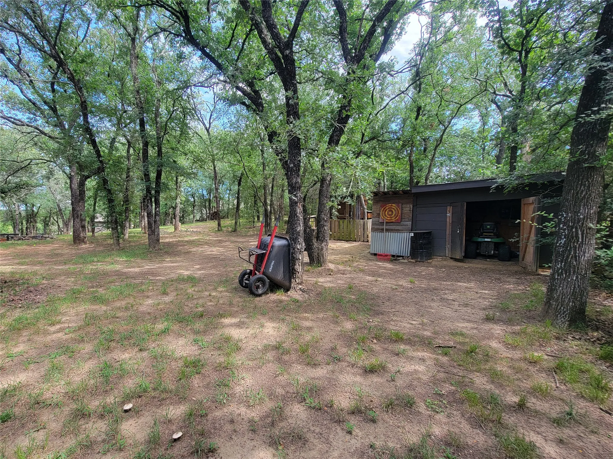 Wooded lot featuring a detached shed with an open bay