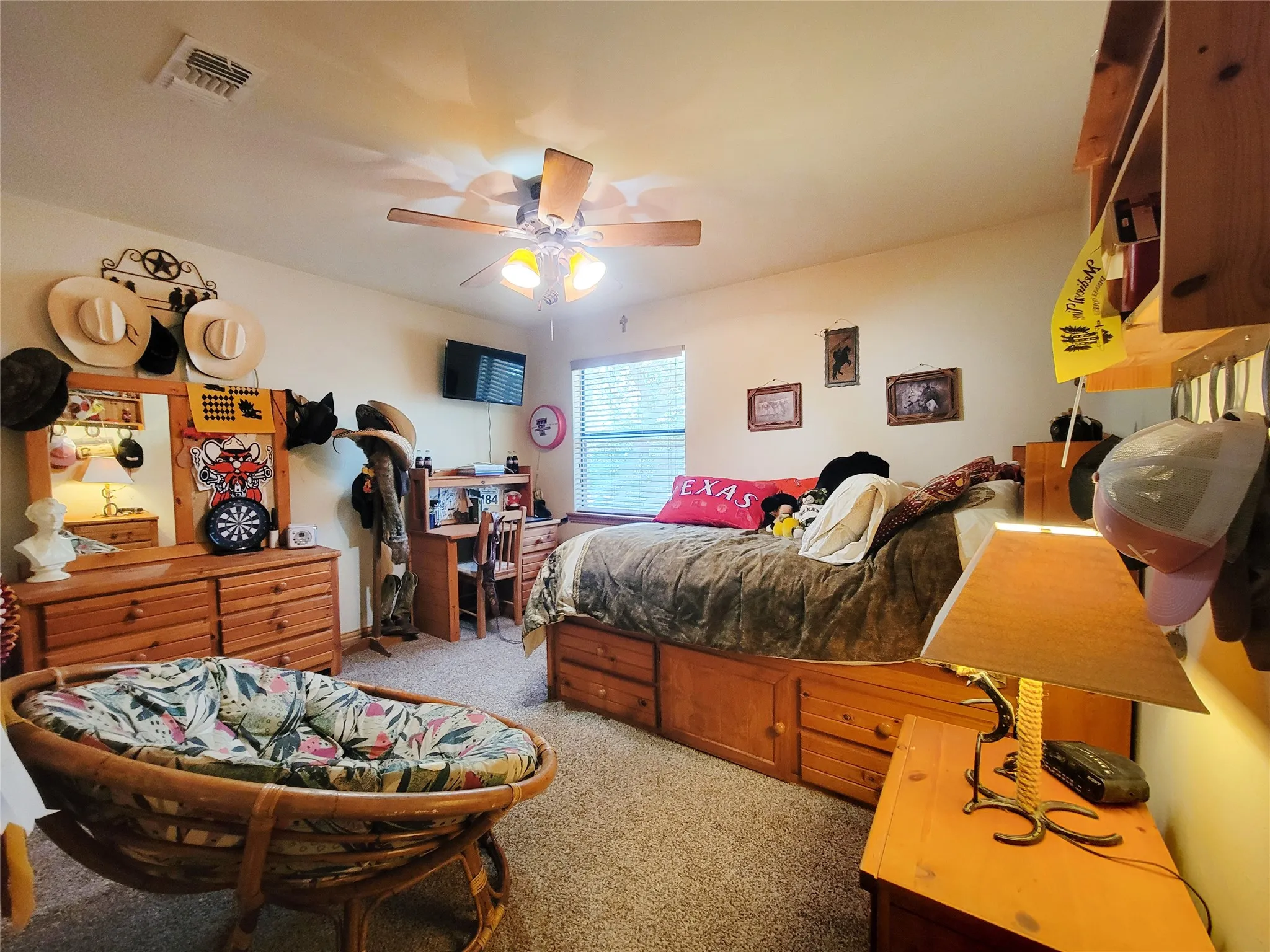 Carpeted room with a ceiling fan, window with blinds, and built-in wood-finish cabinetry