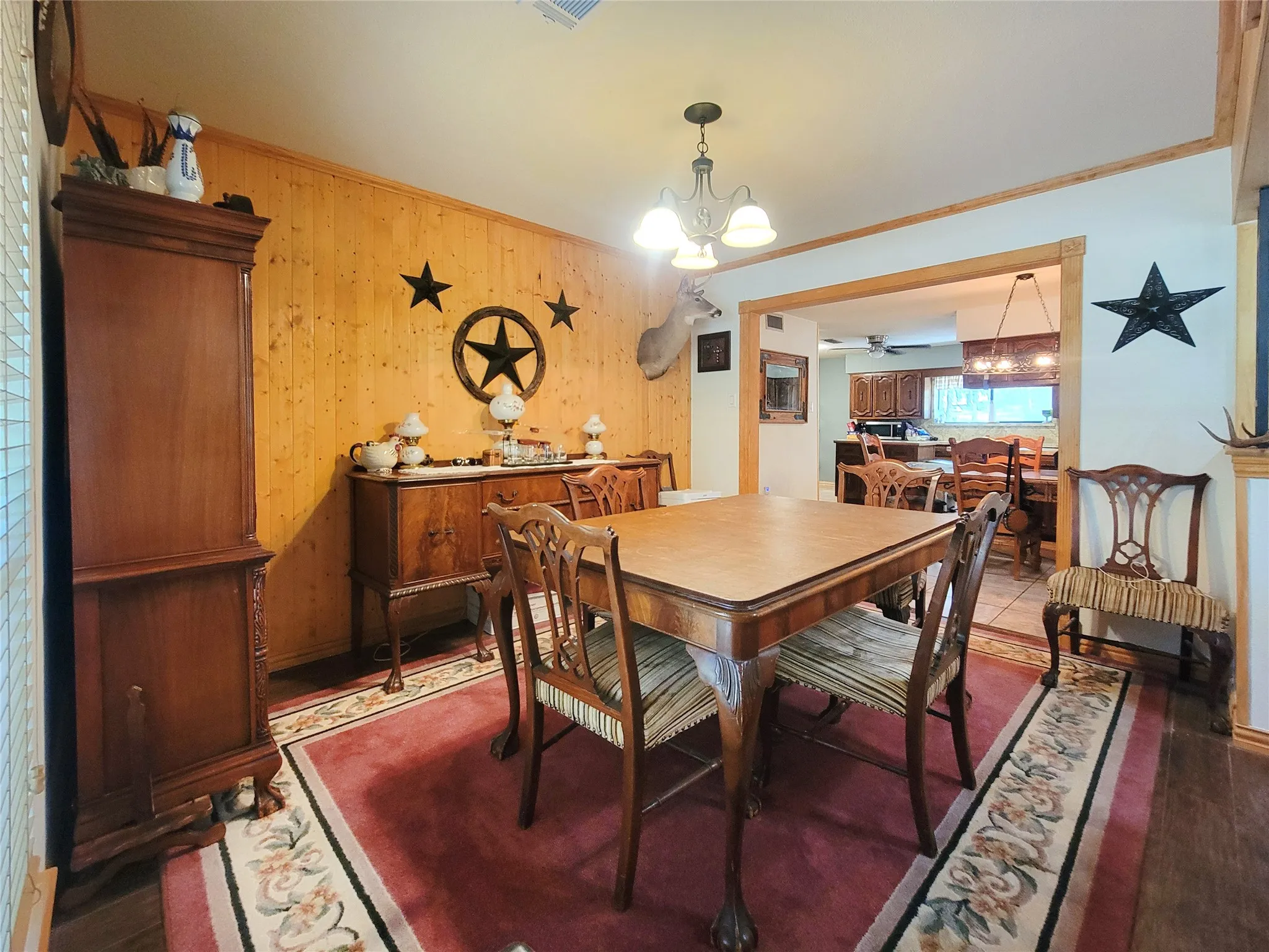 Wood-paneled wall, overhead chandelier, and wood-finish flooring