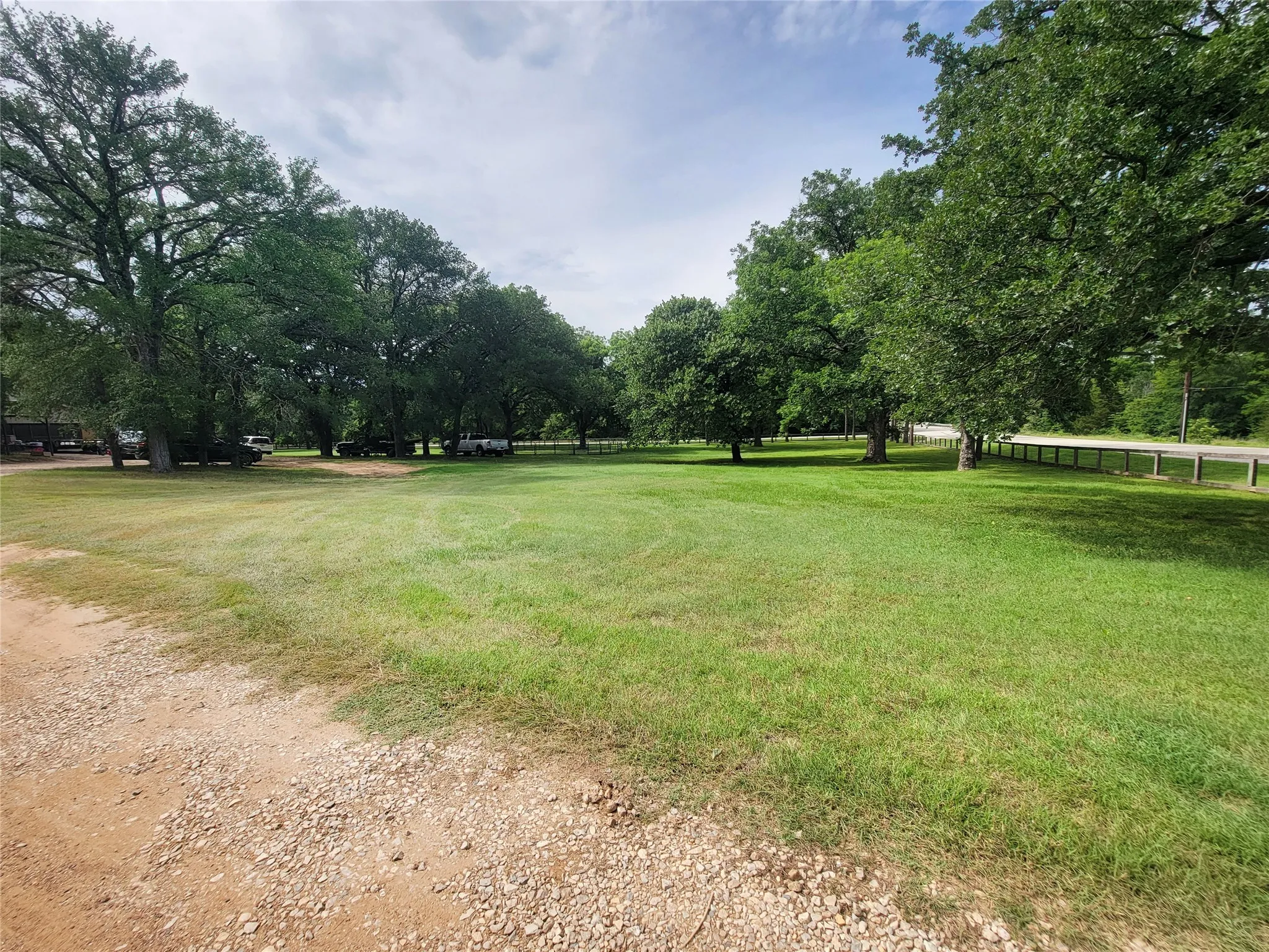 Expansive grass lawn bordered by mature trees and a gravel pathway